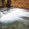 Water Cascading Over A Ledge in a River with The Riverbank Covered with Autumn Poster Print by Reynold Mainse 38 x 24 - Large
